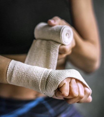 Female boxer putting a strap on her hand
