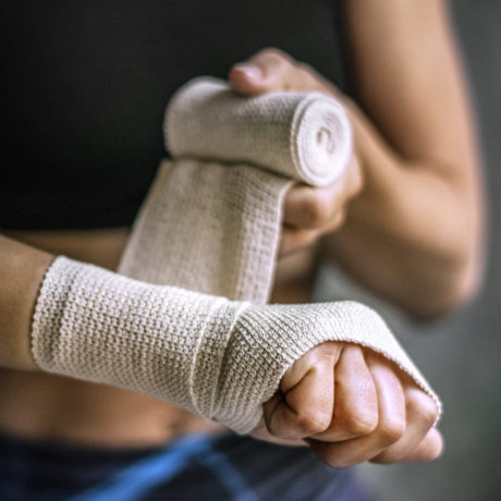 Female boxer putting a strap on her hand